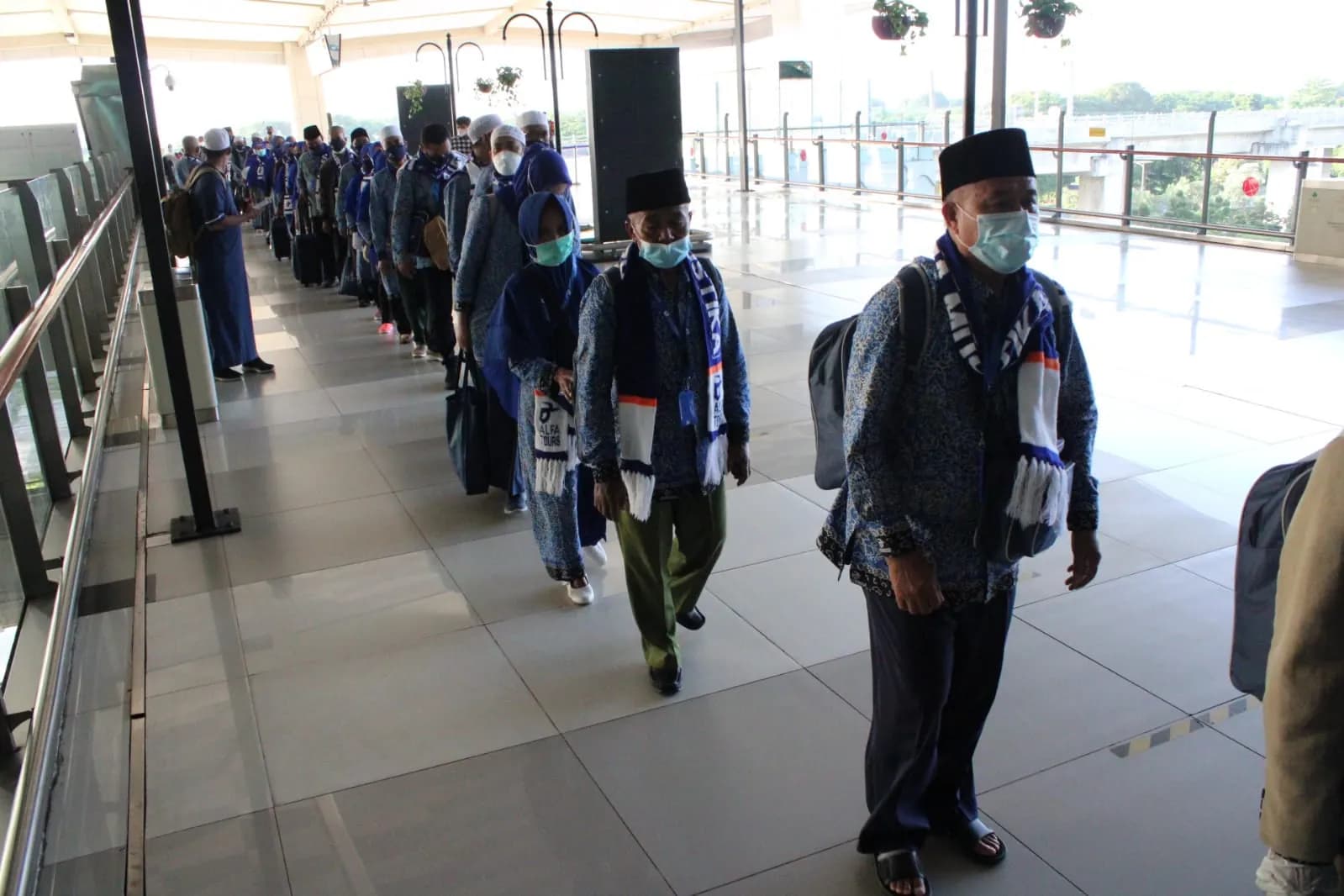 Jamaah umroh Alfa Tour berbaris menuju pesawat dengan syal rombongan