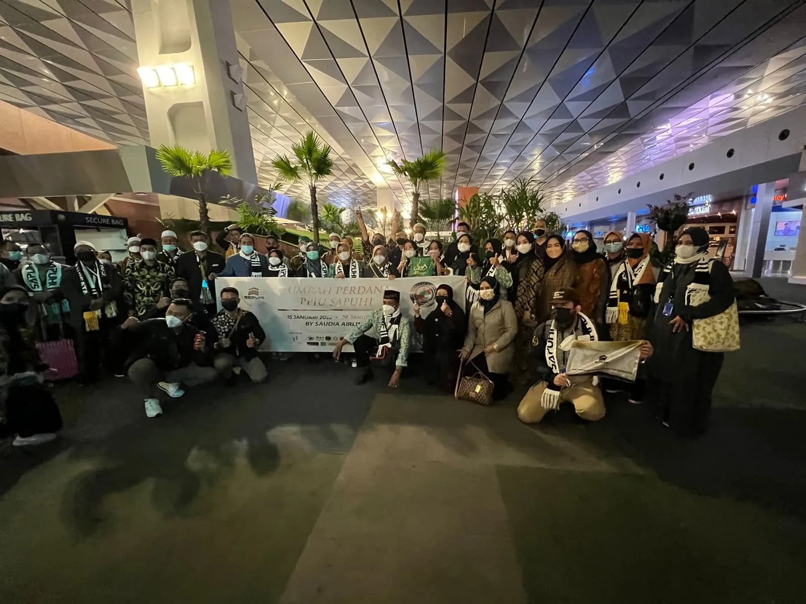 Rombongan Umrah Perdana PPIU SAPUHI dengan spanduk di Bandara Soekarno-Hatta